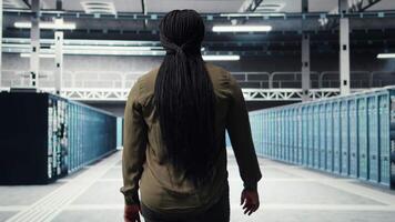 kvinna gående genom data Centrum server rader, kontroll Utrustning för systemet stabilitet. den professionell övervaka server odla, övervakning infrastruktur stordatorer, kamera en video