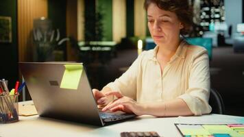 stänga upp av kvinna spenderar de natt transkribering nyckel poäng, skriver på henne bärbar dator. skapande en sammanfattning, korrekturläsning tal och design en strategi till justera med företag mål. kamera a. video