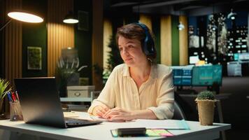 Focused consultant takes notes during executive board meeting call, extracting essential bullet points from the discussion with business associates. Late night briefing session. Camera A. video