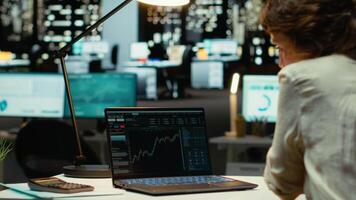 kvinna analytiker övervakning och dokumentera global marknadsföra framsteg trender, forex data i kontor efter timmar. applicering finansiera insikter och ekonomisk analys för organisatoriska tillväxt. kamera b. video