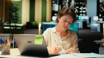 mujer de negocios hace Error en transcribiendo Finanzas actualizaciones en computadora portátil, desgarro arriba el papel sábana y reiniciando. descontento impaciente trabajador falto a terminar Tareas para el noche. cámara b. video