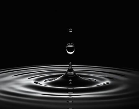 Closeup of a single water drop creating ripples on a dark surface, capturing the moment of impact and splash photo