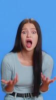 oh meu Deus, uau. animado espantado vencedora mulher levantando mãos dentro surpresa olhando às Câmera com grande olhos, chocado de de repente vitória. sincero atraente menina isolado sozinho em azul estúdio fundo video