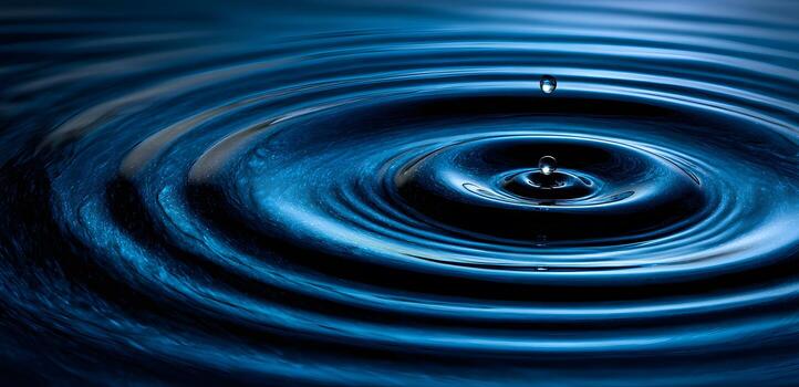 A dark blue liquid surface displays concentric ripples from a falling drop, creating a mesmerizing and tranquil effect. photo