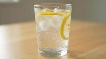 Gießen Wasser in Glas mit Eis und Zitrone Scheiben auf ein hölzern Tabelle beim tagsüber video