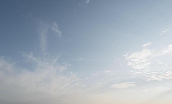 Blue sky with scattered white cirrus clouds. The clouds vary in size and shape, creating a serene atmosphere. Background light blue. photo