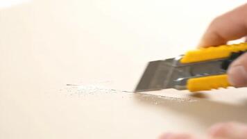 utilizzando utilità coltello per tagliare su un' leggero superficie nel un interno ambientazione video