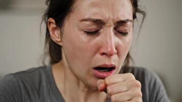 Frau mit Tränen im Augen sieht aus erschrocken und Husten beim Zuhause während tagsüber video