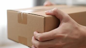 person bärande rektangulär kartong låda med händer i främre av en suddig bakgrund video