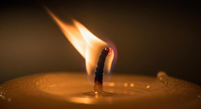 Close up of a single candle flame burning with a warm glow in a dark, peaceful setting photo