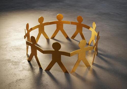 Golden paper figures forming a circular human chain on a concrete surface, symbolizing unity and teamwork photo