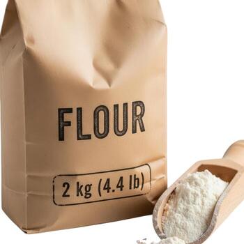 A bag of flour with a wooden scoop isolated on white background, showcasing baking ingredients and preparation photo