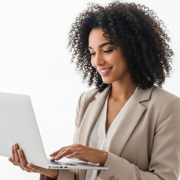 Smiling woman with curly hair in a blazer working on a laptop computer photo