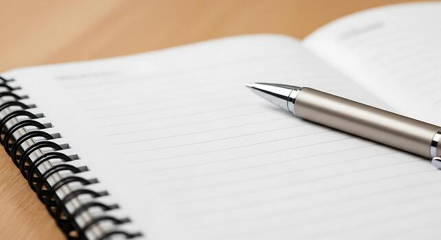 A close up shot of a silver pen resting on an open notebook with lined paper and a spiral binding edge photo
