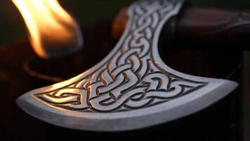 tillverkad yxa med invecklad Nordisk mönster varelse uppvärmd förbi en små ficklampa i en verkstad video