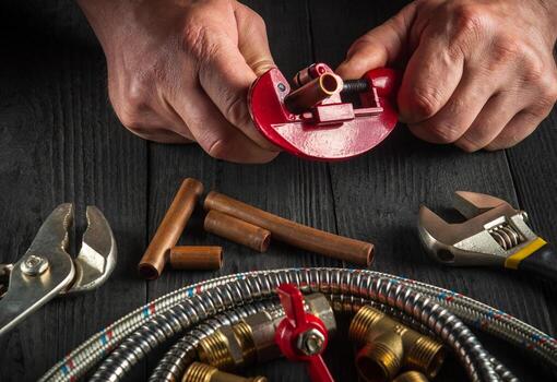 Master plumber cuts copper pipes to install a gas pipeline. Close-up of the hands of the master while working in the workshop photo