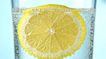 Zitrone Scheibe fallen in funkelnd Wasser im Glas auf Licht Blau Hintergrund video