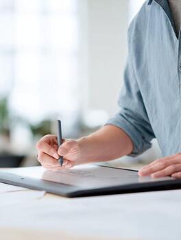 Focused creative professional artist sketching new design, working on project. Close up of hand drawing with stylus on digital graphic tablet at desk photo