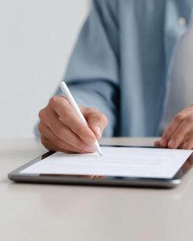 Focused person signing digital contract on tablet. An electronic signature on document for business agreement. Modern and paperless technology for work photo