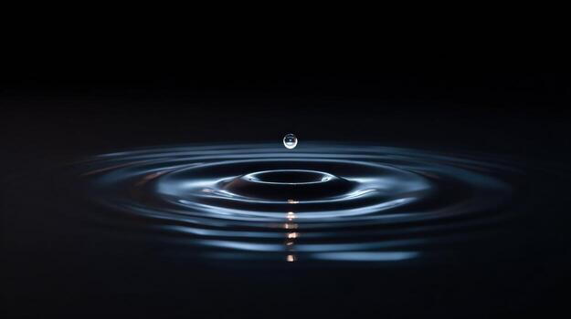 Single drop of liquid falls into calm dark pool creating serene ripple effect. beautiful concentric circle and reflection evoke feeling of tranquility and peace photo