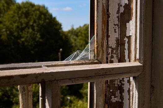 An Abandoned Window Featuring Broken Glass Set Within a Rustic and Charming Environment photo