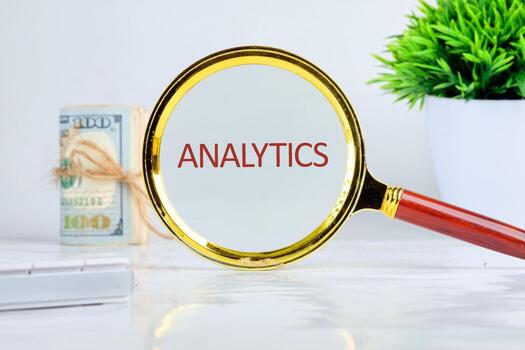 A magnifying glass highlights the term analytics, emphasizing its importance in technology and business growth, alongside currency in the background photo