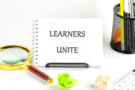 A collaborative environment showing a sign that says learners unite with study tools and crumpled papers scattered on a desk photo