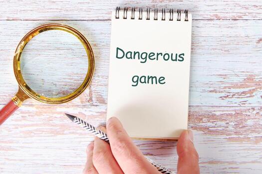 Text Dangerous game It is written in a clean open notebook photo