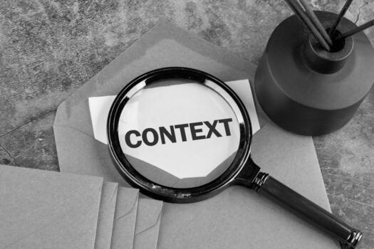 Conceptual context symbol. Copy space. Context word written on a blank sheet peeking out of an envelope through a magnifying glass, a conceptual black and white photo