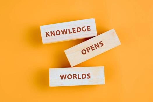 Education,student,university concept. KNOWLEDGE OPENS WORLDS assembled from blocks on orange background, top view photo