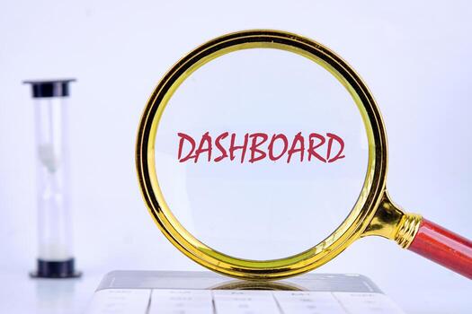 DASHBOARD word was revealed through a magnifying glass on a light background that was on the calculator. Analyst working with Financial Report and Business Analytics concept photo