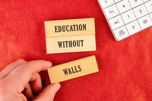 Education concept. EDUCATION WITHOUT WALLS words assembled from blocks in a composition with part of a white calculator and a hand, top view photo