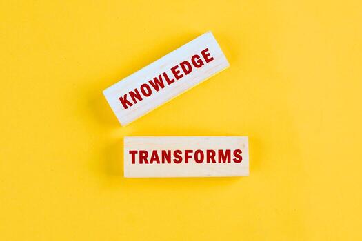 KNOWLEDGE TRANSFORMS concept words assembled from blocks on yellow background, top view photo