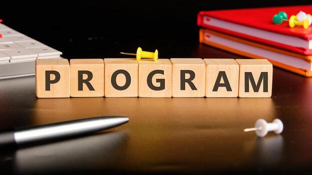 The concept word PROGRAM is collected of wooden cubes on a black background with stationery next to it. Loyalty Program Shopping concept photo