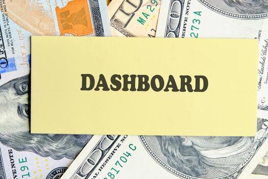 DASHBOARD word written on yellow paper on the background of banknotes. Analyst working with Financial Report and Business Analytics concept photo