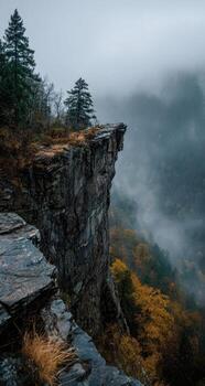 A view of the mountains and fog from the top of a cliff photo