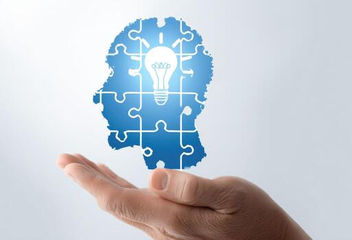 A hand holding a puzzle piece with a light bulb in it photo