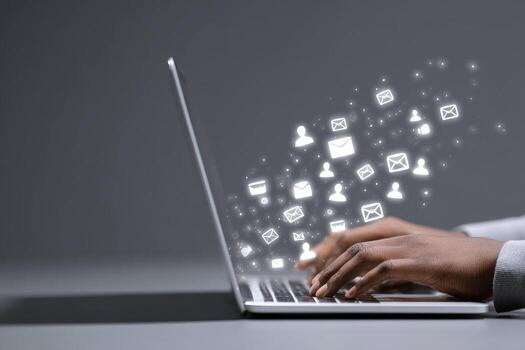 A person typing on a laptop with social icons coming out of the screen photo