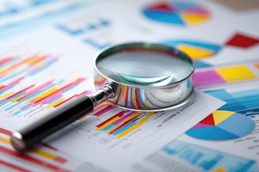 Magnifying glass on financial reports and graphs photo