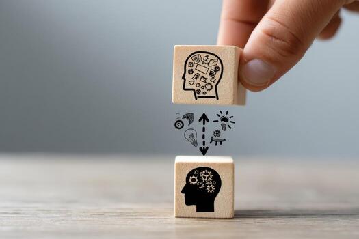 A person is holding wooden blocks with a brain and a person's head photo