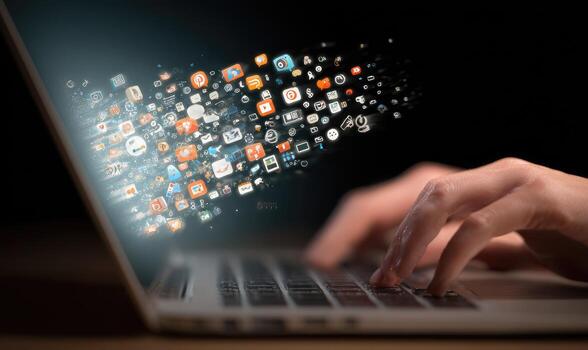 A person typing on a laptop with social icons coming out of it photo