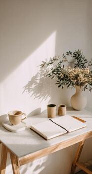A desk with a notebook, coffee cup and vase photo