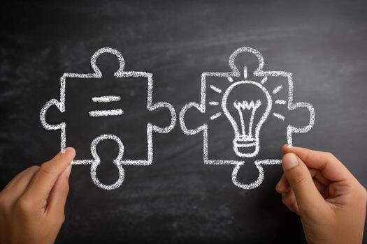 Two hands holding two pieces of puzzle with light bulb on them photo