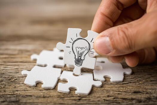A hand holding a piece of jigsaw puzzle with a light bulb on it photo