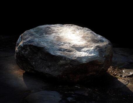 A large rock sitting on the ground with a light shining on it photo