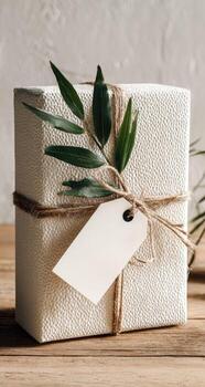 Gift wrapped in white paper with a tag and a green branch photo