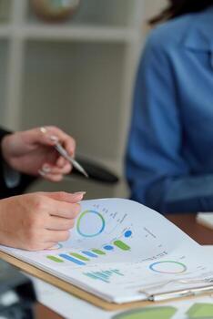 Data Analysis. Close-up of professionals reviewing business reports and graphs in a meeting. photo