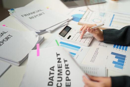 Data Analysis. Accountant using calculator to analyze financial reports and documents. photo
