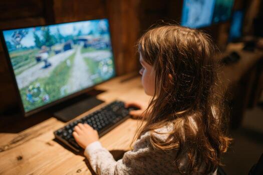 A child focuses intently on a computer screen while playing an interactive game at a technology center in the evening. The atmosphere is cozy and innovative photo