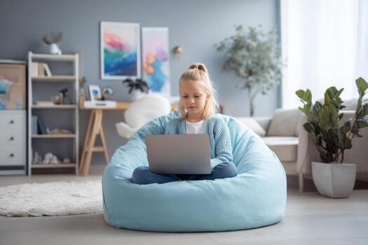 Child sits comfortably on a soft beanbag in a well lit living room, focused on a laptop displaying an online language class. Natural light floods the room photo